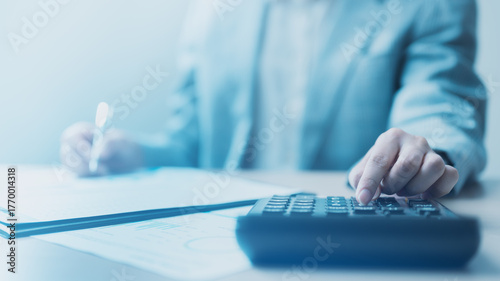 calculator, budget, tax, accounting, Business person using calculator and reviewing financial documents, symbolizing accounting, budget planning, and tax calculation for financial management.