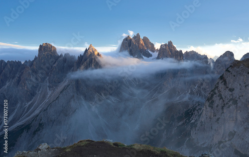 Dramatic landscape with sharp jagged peaks of Cadini di Misurina piercing through clouds and mist, Tre Cime di Lavaredo in Dolomites. Gorgeous rock pillars at sunset. Discovery the beauty of earth.