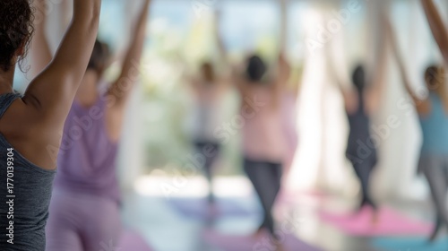 Group of people in a yoga class. they are all wearing workout clothes and are standing on pink yoga mats.