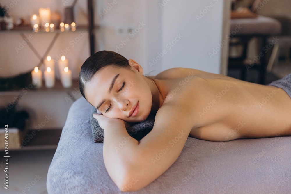 Obraz premium Client enjoying a relaxing massage therapy session in spa with candles