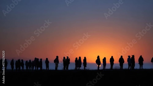 Individuals stand in silhouette as they enjoy a beautiful sunset together, sharing moments