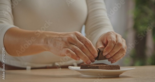 Papier peint Close up of hands breaking crispy chocolate wafers onto a white plate, demonstrating how to make a homemade dessert