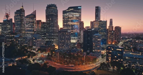 Australia, Sydney: Amazing Sydney's skyline cityscape at dusk, illuminated skyscrapers buildings, flowing night traffic, cars driving road, streets and iconic Sydney Tower. Aerial drone flight footage