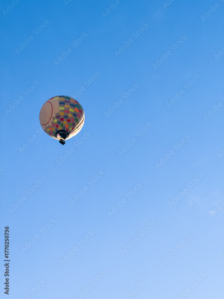 Naklejka premium A hot air balloon flies over the city Yerevan, background of the blue sky. Aerial view of many colorful hot air balloons fly in the sky. High quality