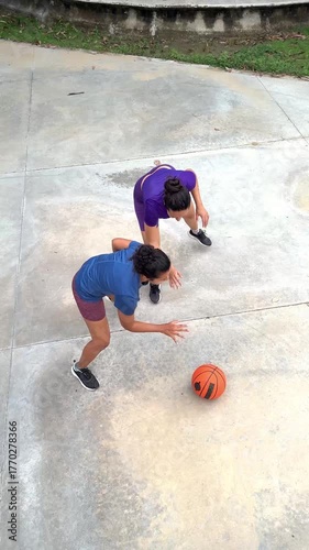 High angle view of two young women playing basketball one on one on an outdoor concrete court