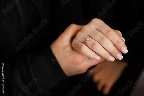 Romantic Engagement: Couple's Hands with Diamond Ring, Black Clothing, Intimate Moment, Love, Commitment, Soft Lighting, Close-up View, Modern Style.