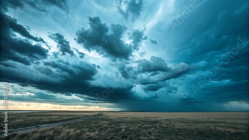 Heavy storm clouds, vast empty landscape, moody blue and gray sky.