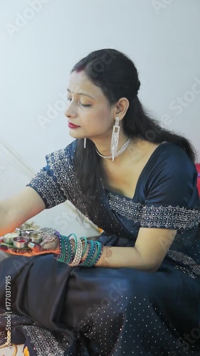 Indian woman in blue saree holding a decorated thali during a festive ceremony
