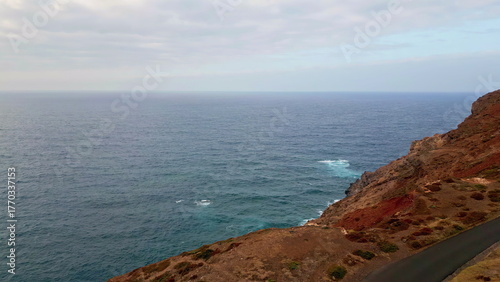 Drone deep blue ocean water crashing dangerous rocky shoreline creating foam.
