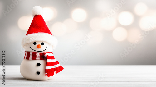 A Christmas snowman on a white snow landscape. Behind the snowman is a bokeh glitter background. Copy space area for text