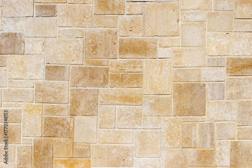 Facade or wall texture paved with square and rectangular tiles of natural beige sandstone Natural stone background for design construction and architecture