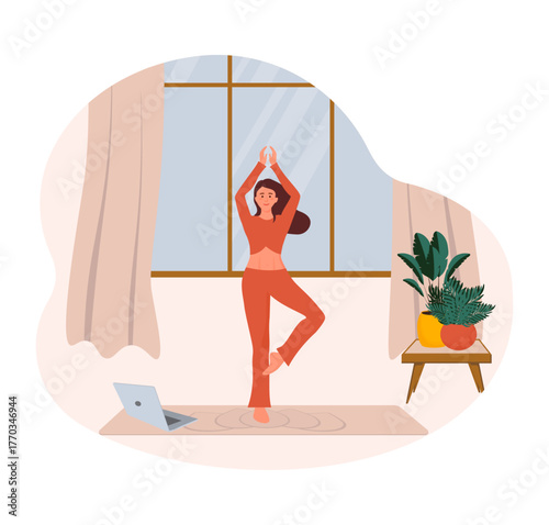 Woman practicing yoga tree pose during online class at home