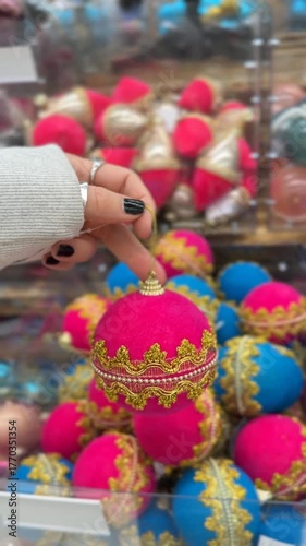 Christmas ornament held by hand in store aisle with blurred festive decorations background