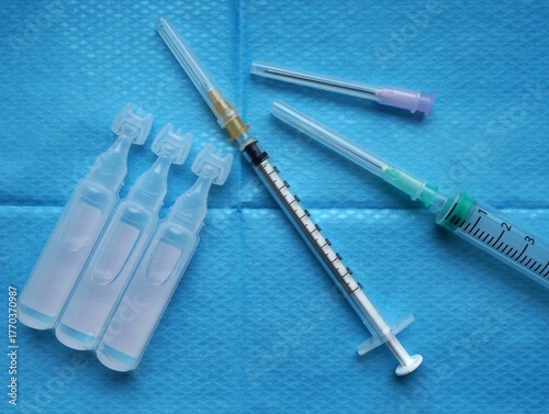 Ensemble de seringues, aiguilles et unidoses de sérum physiologique sur fond de champ stérile hospitalier