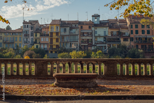 Stone bench on the Parma riverfront. Typical Parma houses. Colorful houses along the riverfront. Autumn.