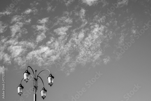 Old street lamp with four lamps. Alone. Bottom view with sky and clouds. Background.