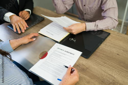 Photos Closeup of couple signing divorce agreement with legal counsel