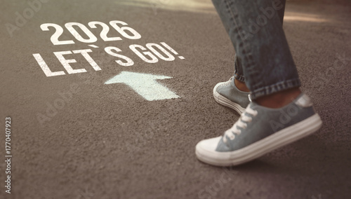 New 2026 Year. Man walking toward arrow with numbers and phrase Let's Go! on asphalt, closeup