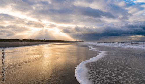 Bild auf Leinwand Idyllic beach panorama on the North Sea island of Norderney in the Wadden Sea National Park (Germany) in the atmospheric golden light of the autumn evening sun, reflected in the water and wave surf