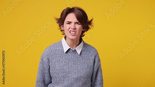 Indignant outraged sad young Caucasian woman she wear grey knitted sweater white shirt casual clothes swearing spread hands say no reject refuse isolated on plain yellow background. Lifestyle concept