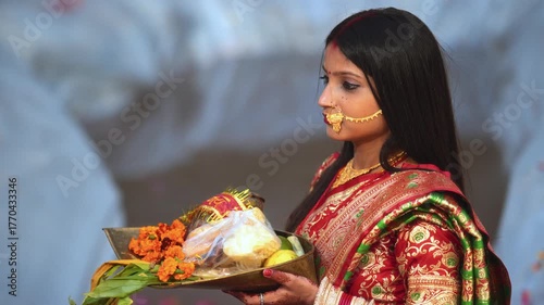 A newly married Indian woman performs Chhath Puja with devotion, holding a traditional soop filled with offerings.