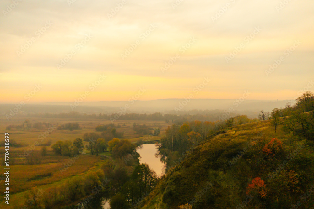Obraz premium Scenic view of a winding river surrounded by autumn fields