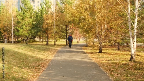 Wallpaper Mural A woman wearing a jacket and hat with Nordic walking poles walks in an autumn city park Torontodigital.ca