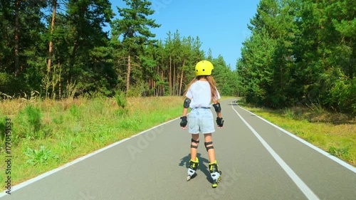 Girl is roller skating by forest, enjoying an active hobby in the open air.