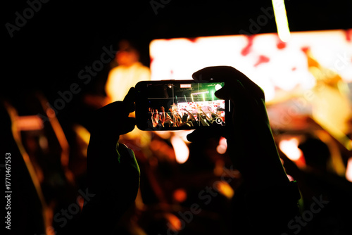 Smartphone recording live concert with bright stage lights
