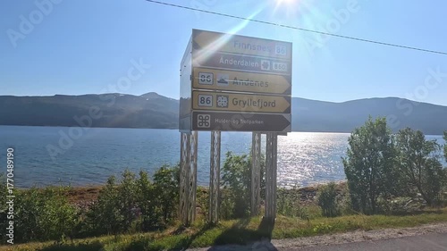 4K video showing a person approaching a road sign in Norway with majestic mountain peaks in the background.
