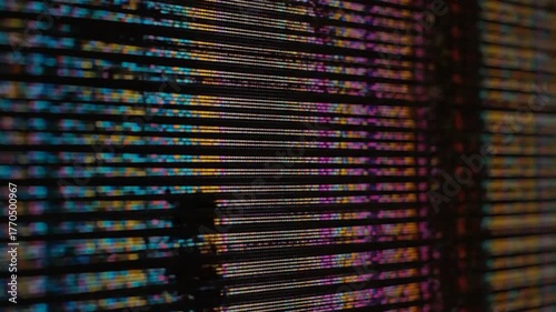 A side view of a screen exhibiting horizontal, colorful, pixelated lines with abstract colors