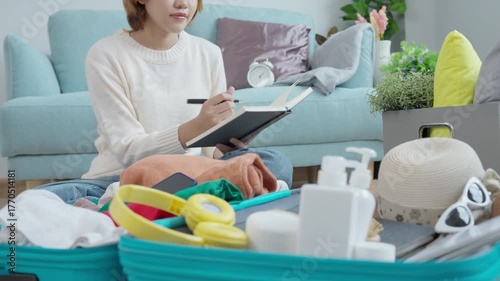Travel bag. female are checking the detail and quantity of items used during the trip by checklist. Young women are prepare clothes and personal belongings. Pack your luggage before travel.