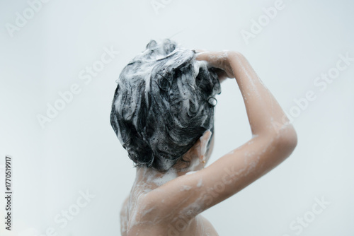 A child washing hair with shampoo foam in the bathroom, showing hygiene and personal care routine.