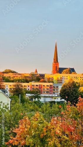 Aussicht auf Chemnitz Sonnenberg mit Plattenbau im Vordergrund. Sonnenuntergang leuchtet die Kirche an.