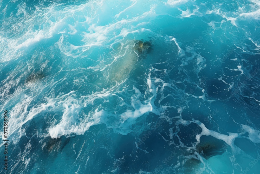 Fototapeta premium Aerial view of turquoise ocean waves creating a dynamic pattern, showcasing the beauty of water and its movement over submerged rocks.