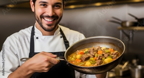 Portrait of a smiling cook holding traditional pan with stew