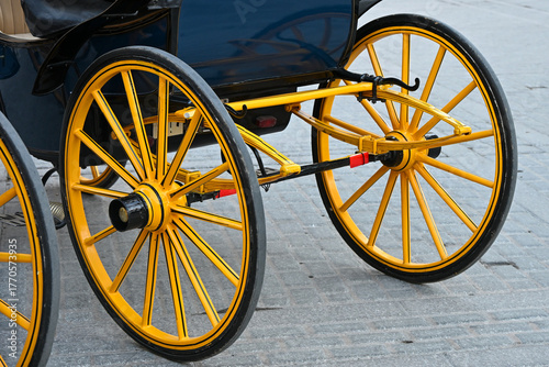Close-up view of a traditional horse carriage wheel in Seville, featuring bright yellow spokes and classic craftsmanship typical of Andalusian street carriages