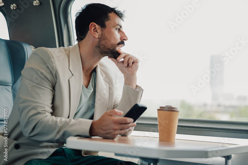Fotografie Man commuting by train, looking out window