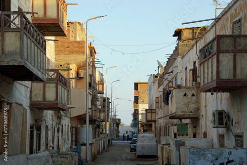 Narrow, dirty dirt road between crumbling multi-story buildings