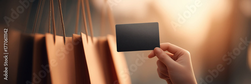 Hand holding credit card against blurred luxury shopping bags background