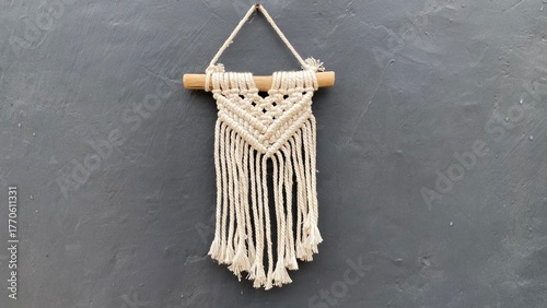 Macrame wall hanging made of simple knitted white wool on a wooden and black wall background