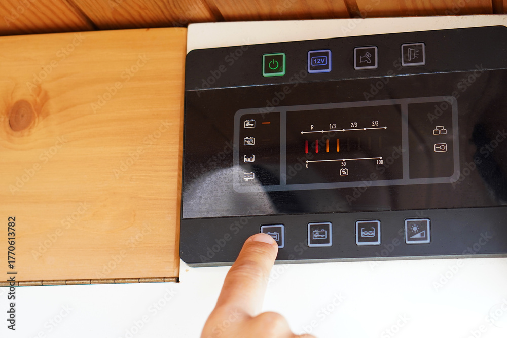 Fototapeta premium A man checking the battery charge level of his solar-powered camper van.