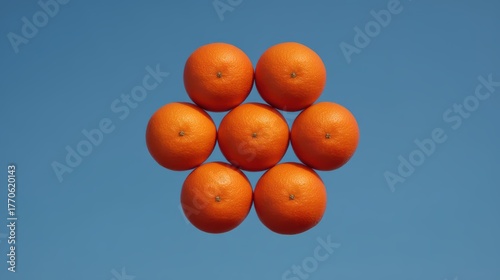 A symmetrical arrangement of bright oranges against a clear blue sky, creating a visually striking and vibrant image.