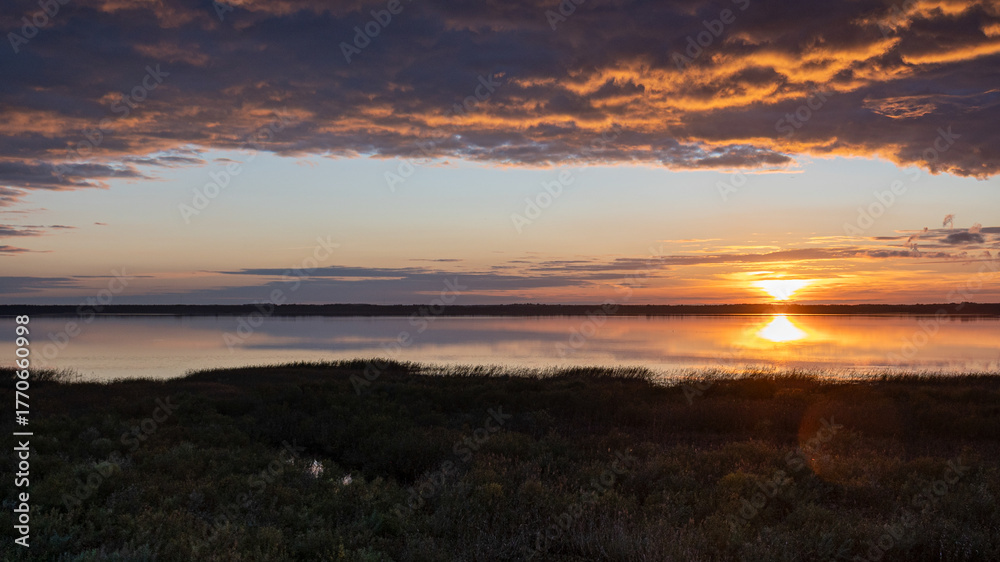 Fototapeta premium wonderful sunset by the lake, autumn landscape, sun rays reflecting on the calm surface of the lake
