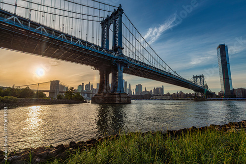 Sunrise over a large suspension bridge with city skyline in the background. New York City, NY, USA Williamsburg Bridge over East River