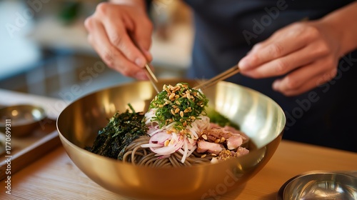 A food stylist, their fingers precise, arranges Pyeongyang Naengmyeon in a yugi brass bowl for a photoshoot, the studio’s lights bright. The bowl’s polished surface reflects, holding noodles in