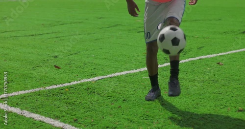 Brazilian man of African descent performing freestyle keepie uppie juggling soccer ball on turf demonstrating talent, coordination and precision during personal training session