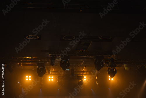 Dim, moody backstage scene with warm amber stage lights