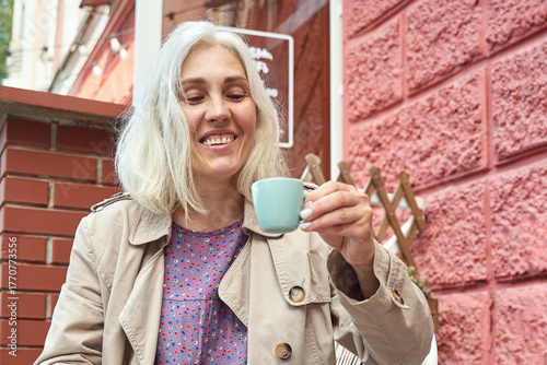 Foto Elderly caucasian female enjoying coffee outdoors in casual attire