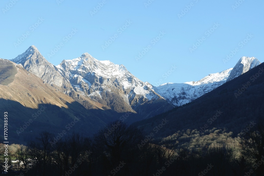 Fototapeta premium Snow-covered peaks rise dramatically against a bright blue sky in the Pyrenees mountains